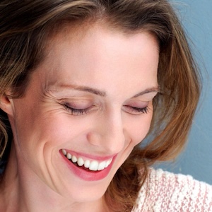 Mujer sonriendo con piel radiante y luminosa, reflejando bienestar y cuidado personal.