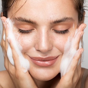 Mujer disfrutando de una limpieza facial con espuma suave para purificar y refrescar la piel.